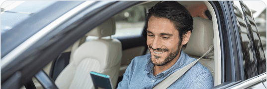 Mulher sorrindo no carro usando celular